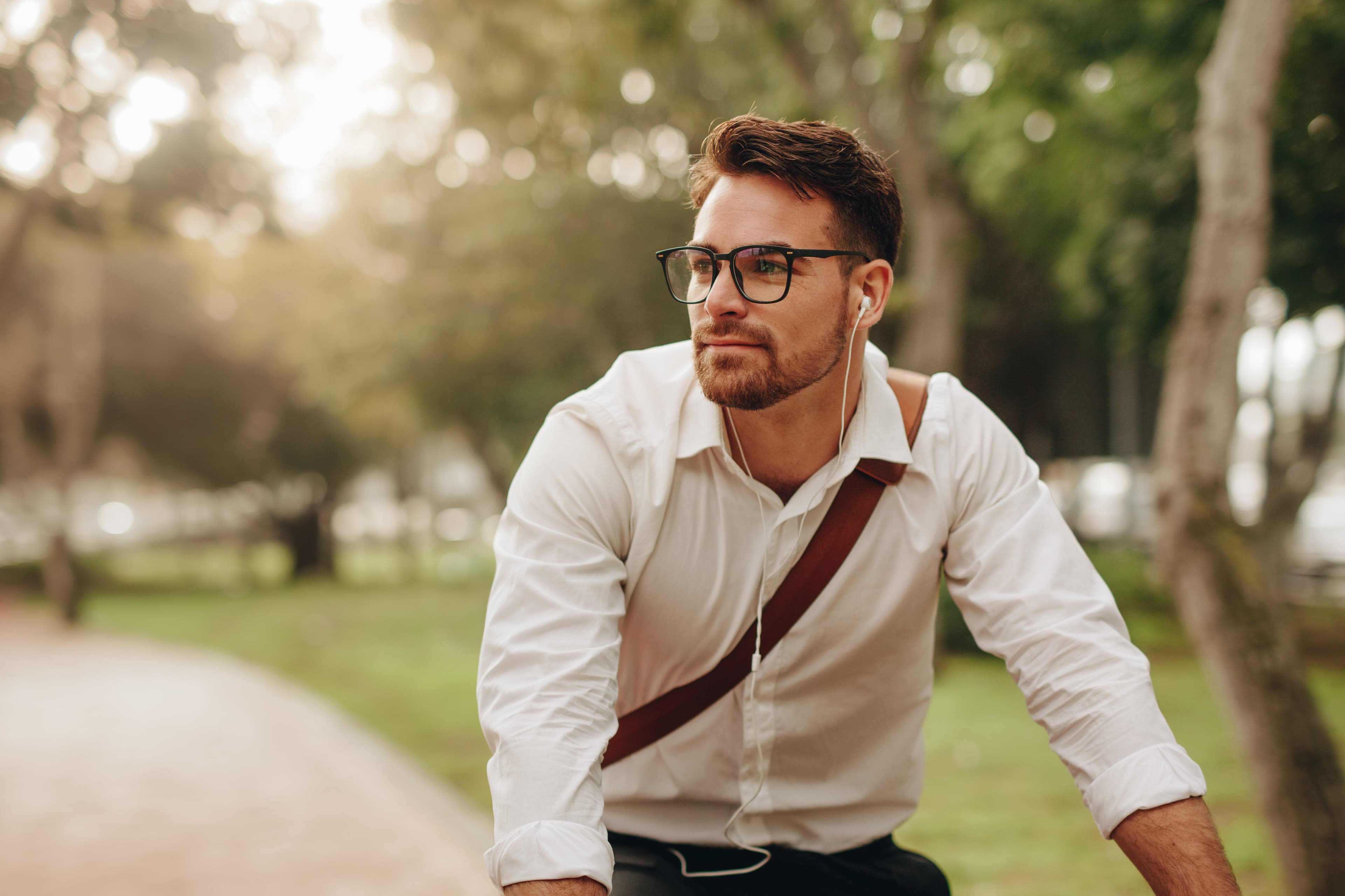 Man enjoying music using earphones while commuting to office on a bicycle. Businessman biking to office while listening to music.